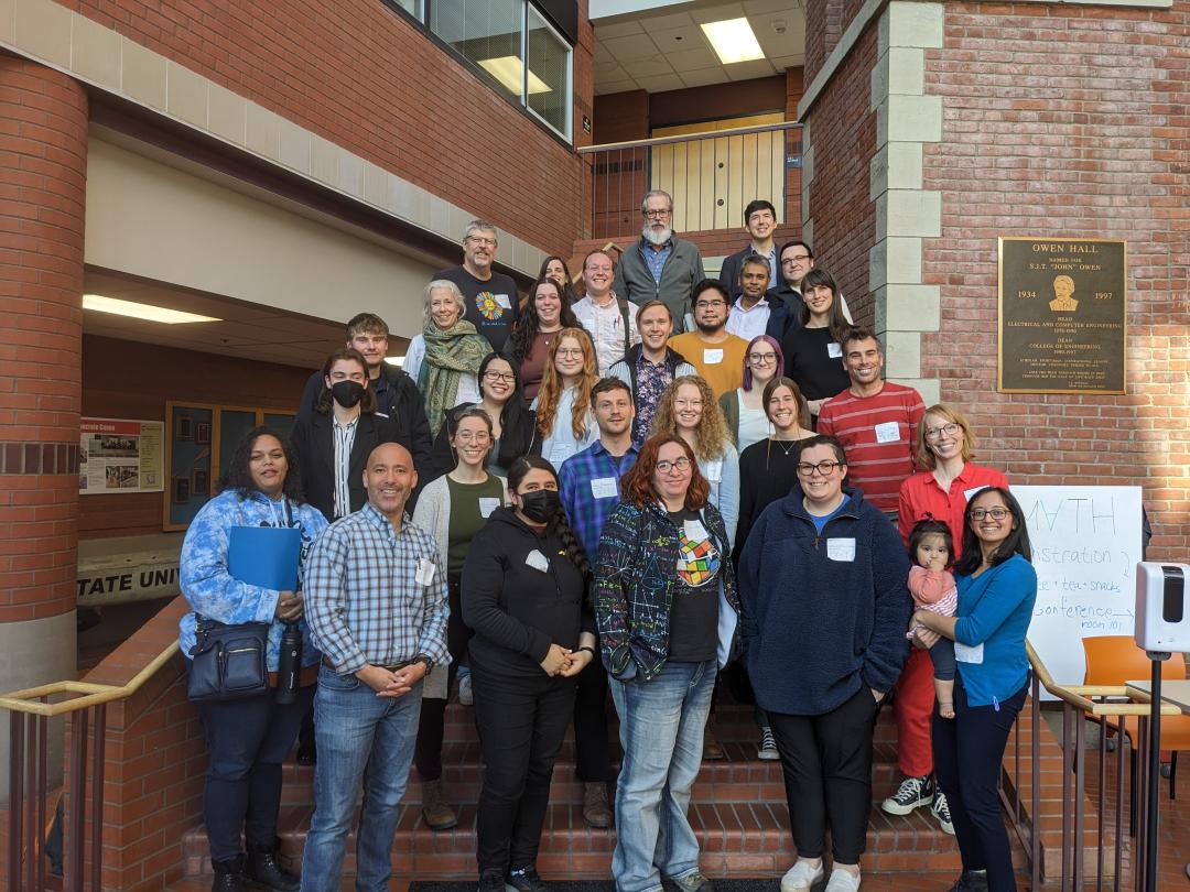 A group of individuals stand on a staircase for a photo during a mathematics conference. 