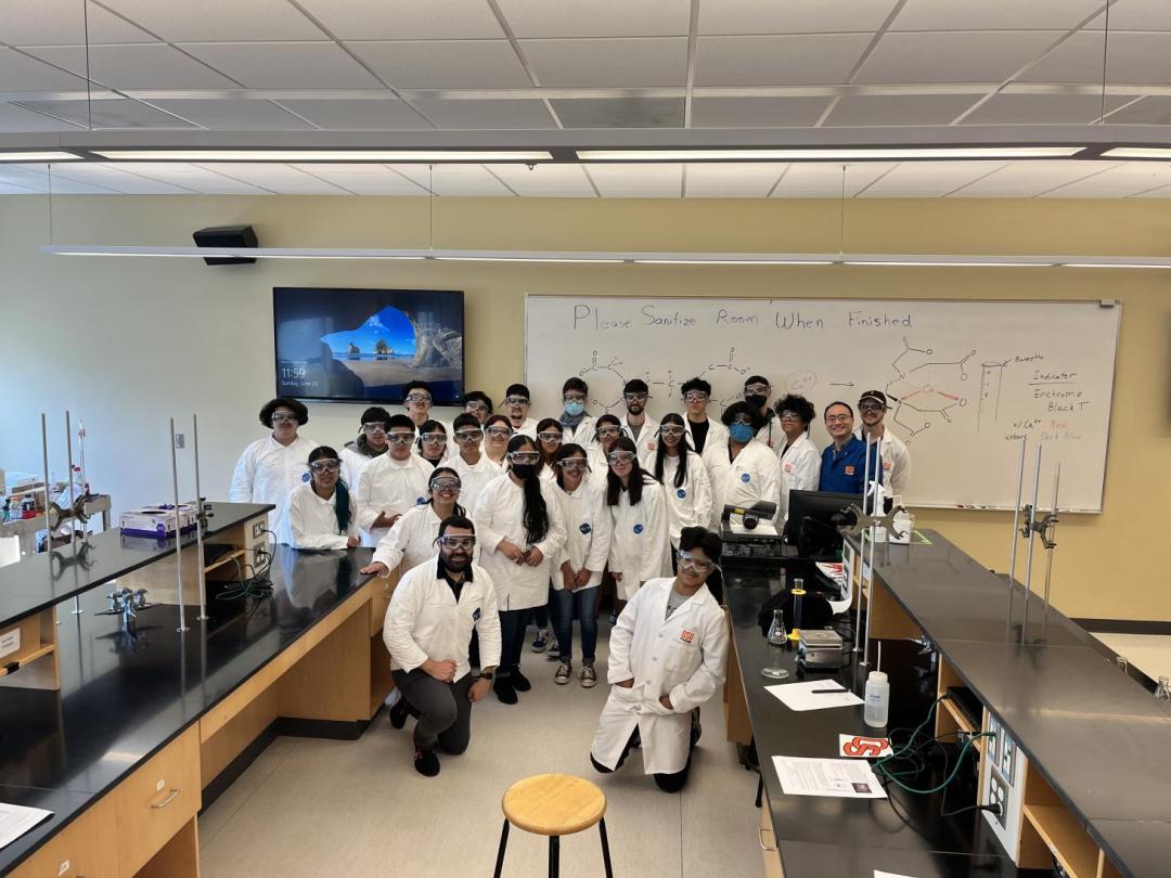 A group of students in white lab coats pose for a picture.