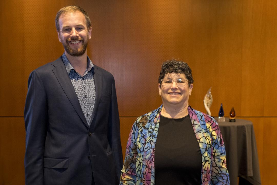 A man and woman stand next to each other wearing professional clothing.