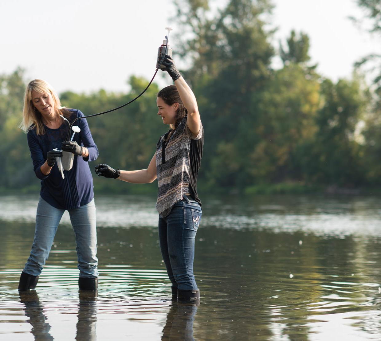 Kim Halsey and Cleo Davie-Martin collecting samples from a river.