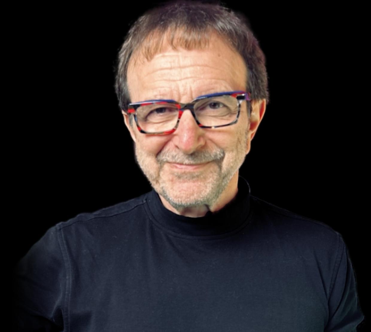 Vincent Racaniello wears a black shirt on a black background. He smiles slyly.