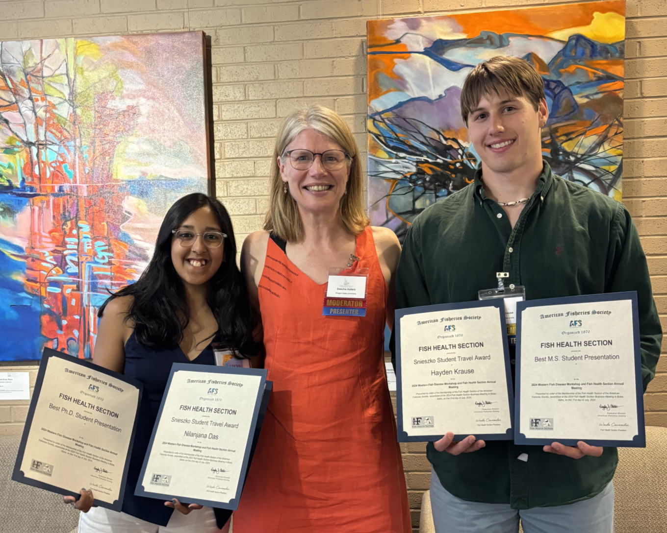 Nilanjana Das and Hayden Krause, holding their awards, stand with their advisor Sascha Hallett.