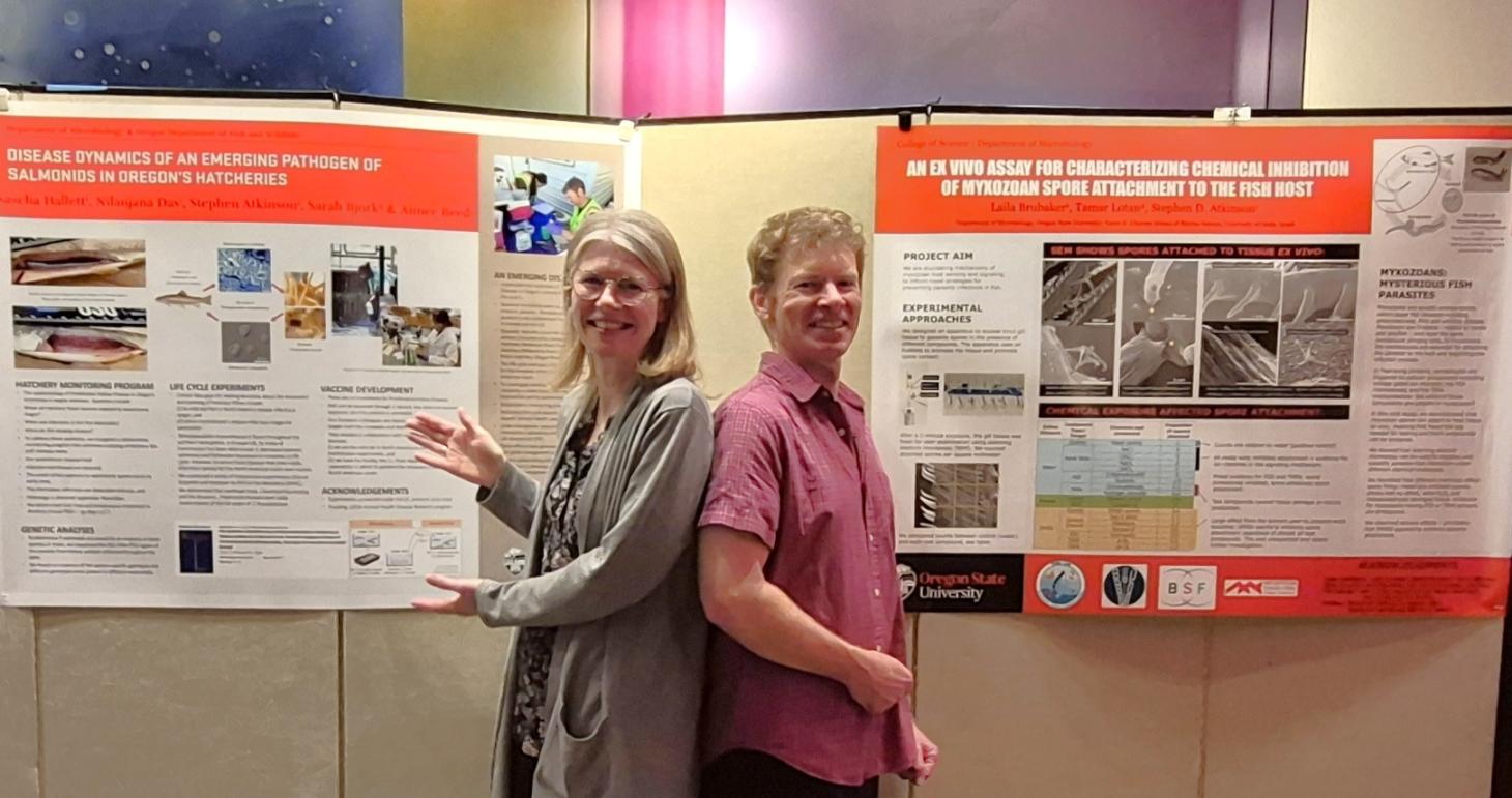 Associate professors Sascha Hallett and Stephen Atkinson stand between two research posters created by the PHIn Lab.