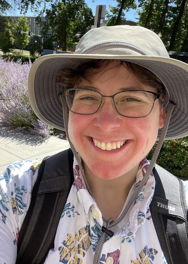 Ashely Stengel outside on a sunny day, wearing a hat and a backpack.