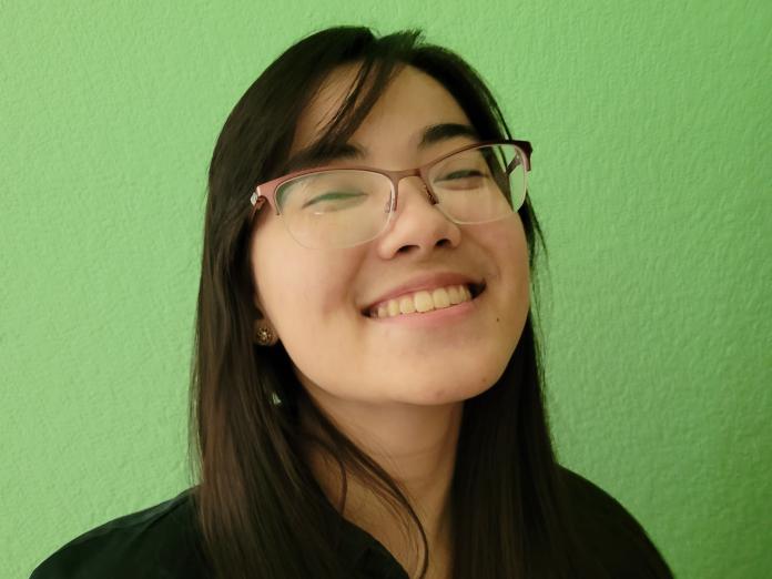 Lynn Kaneko smiling against a green wall.