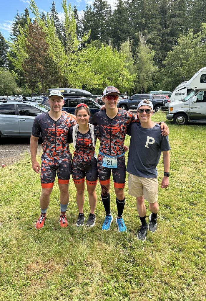 Four people in triathlon gear pose for a photo.