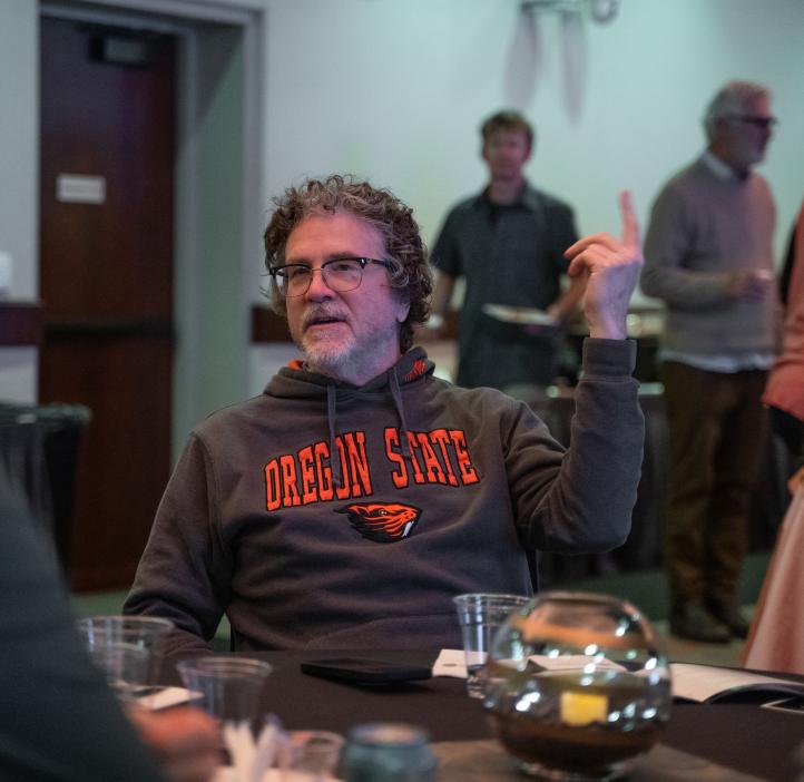 A man in OSU sweatshirt sits at a table.