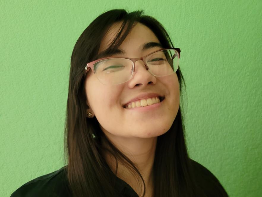 Lynn Kaneko smiling against a green wall.